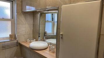 A bathroom with a large mirror, a sink, a towel rack, and a toilet.