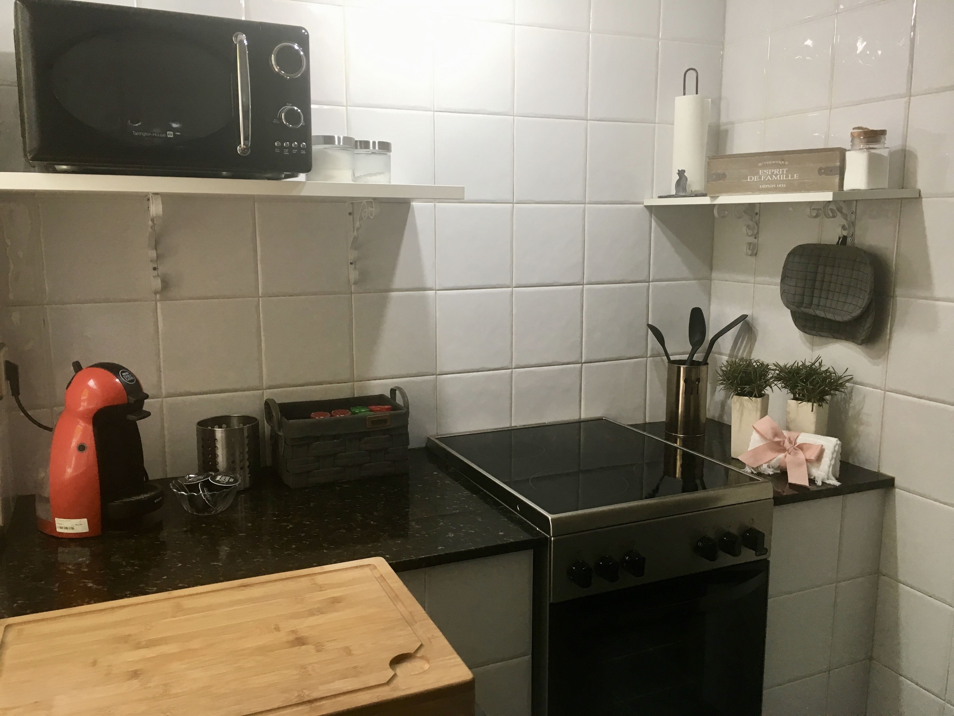 Una cocina equipada con microondas, estufa y varios utensilios.