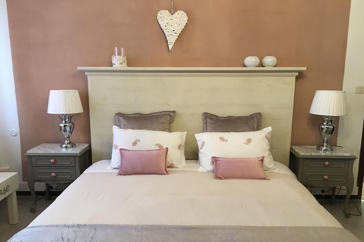 A bedroom with a bed, two nightstands, a dresser, and a wall-mounted heart decoration.