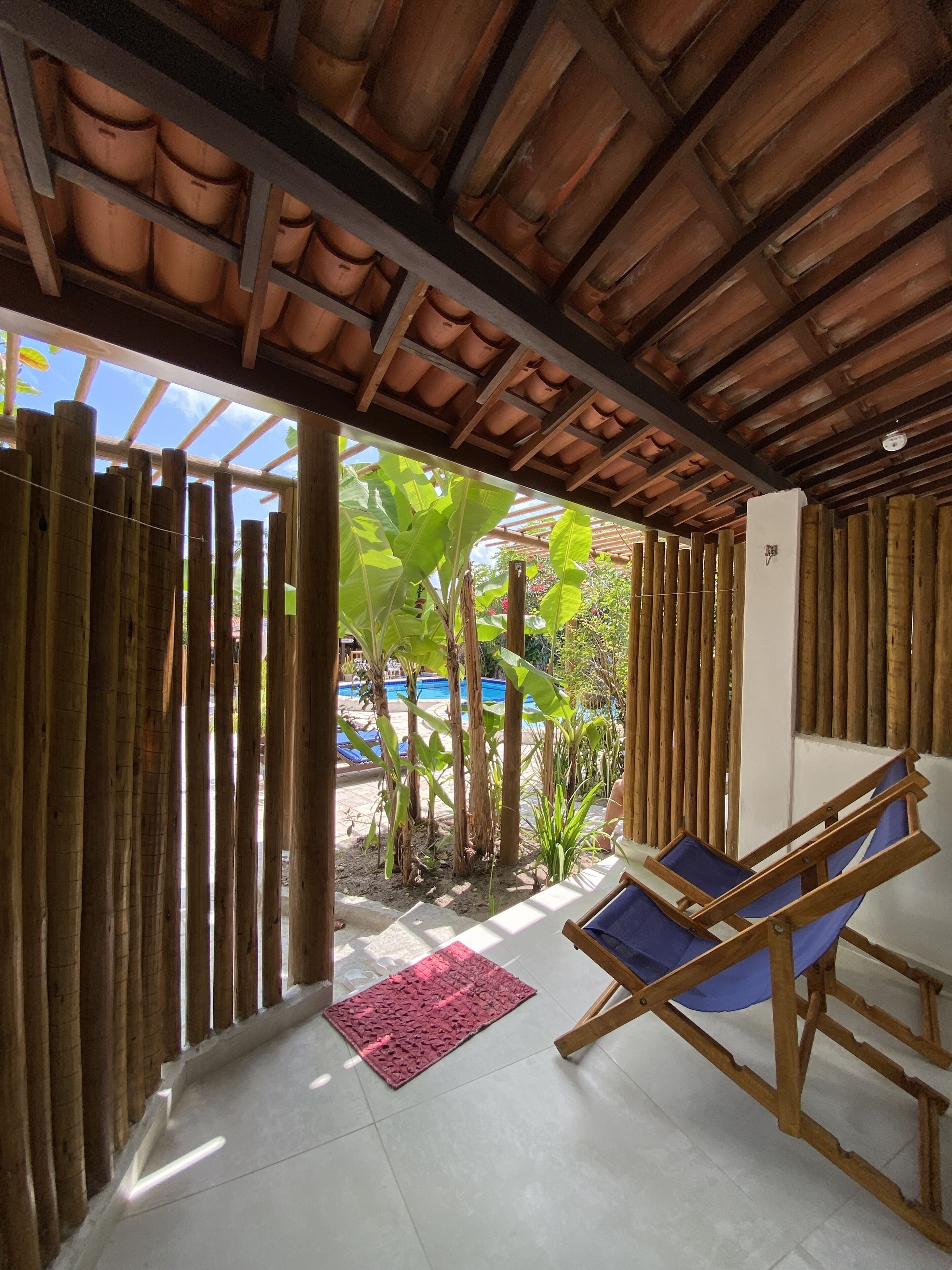 A wooden-framed room with a view of a pool and tropical plants.