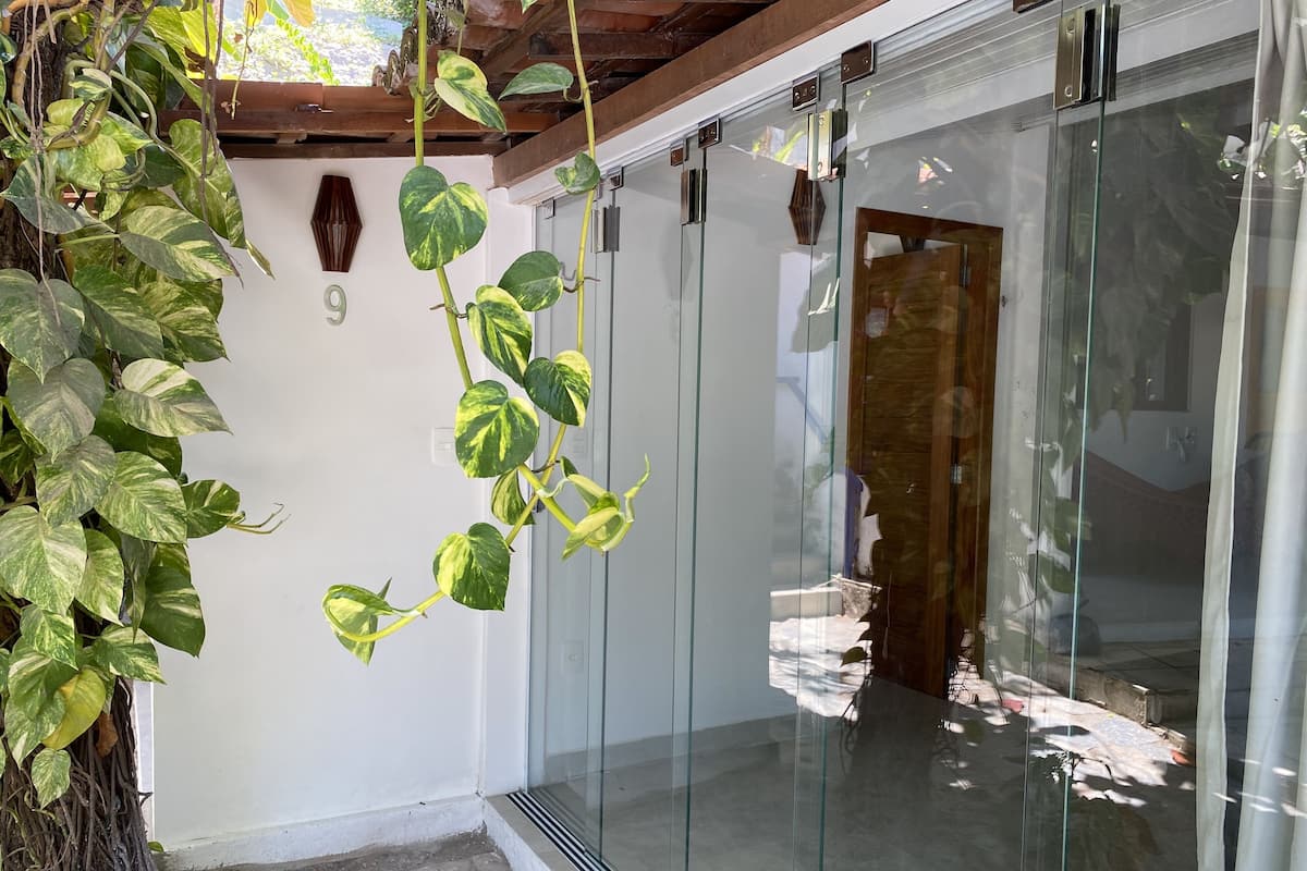 Un interior moderno con puerta de vidrio, techo de madera y planta en maceta con hojas variegadas.