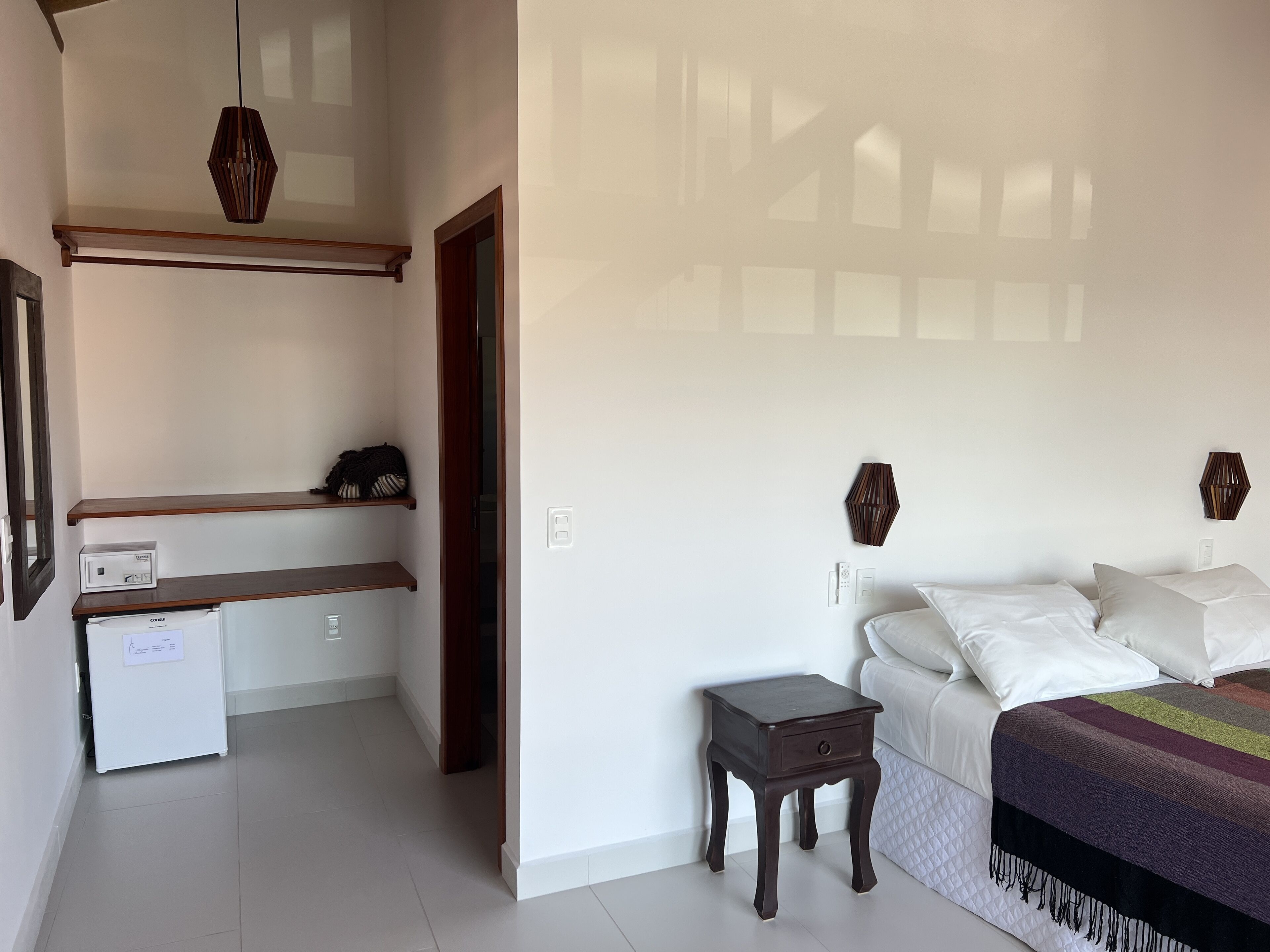 A bedroom with a bed, bedside tables, a wardrobe, and a small desk with a computer.