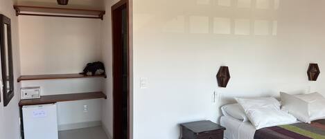 A bedroom with a bed, bedside tables, a wardrobe, and a small desk with a computer.