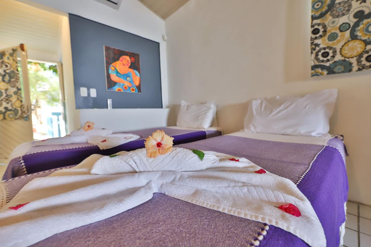 Habitación de hotel con dos camas, un cuadro grande en la pared y una ventana con cortinas.