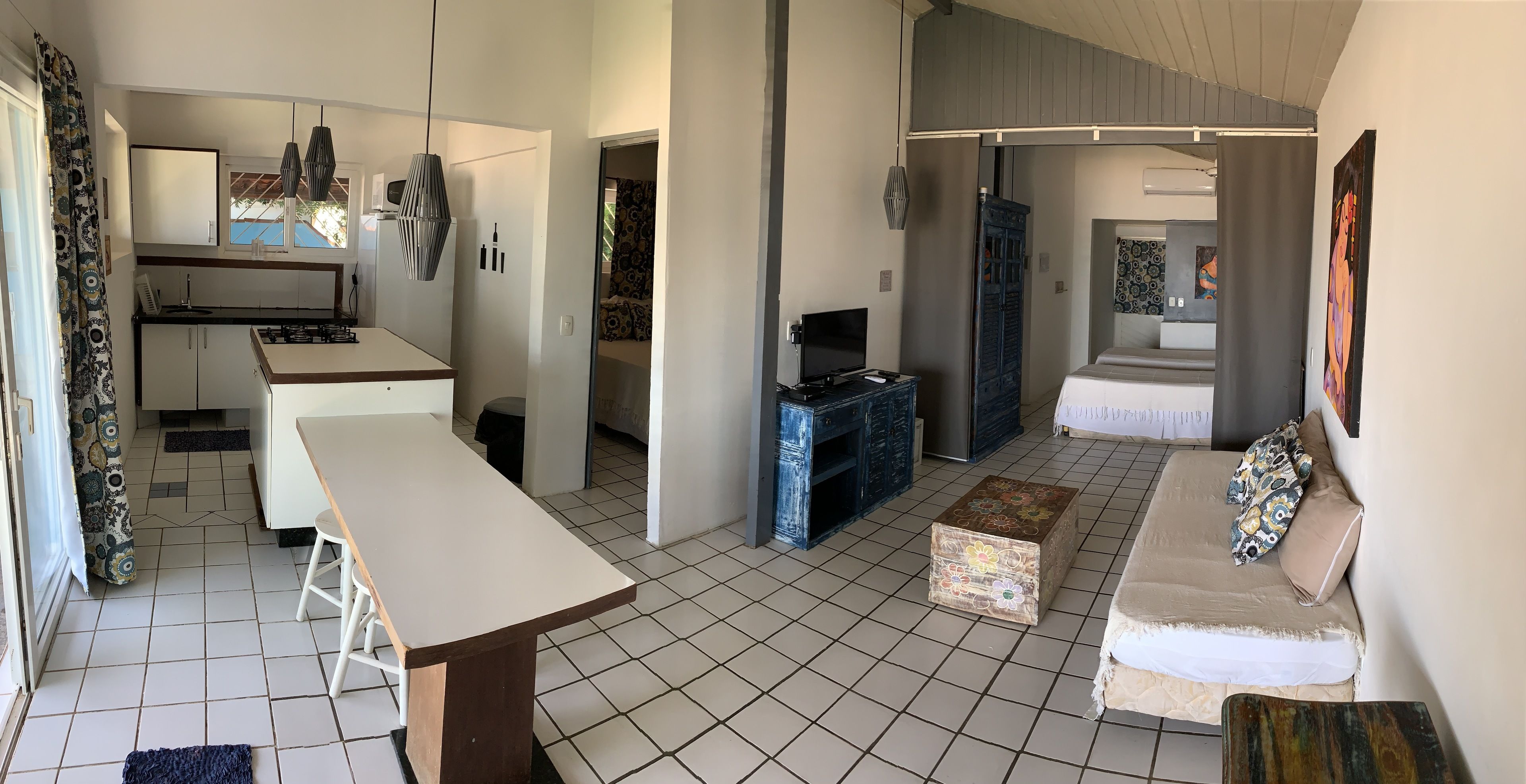 A modern kitchen with a dining area, a sofa, and a TV.