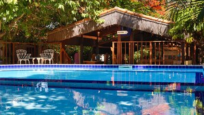 A pool area with a thatched-roof pavilion, a lounge chair, and a sign indicating 'DUCHA'. - Pousada Barbara (Tibau do Sul)