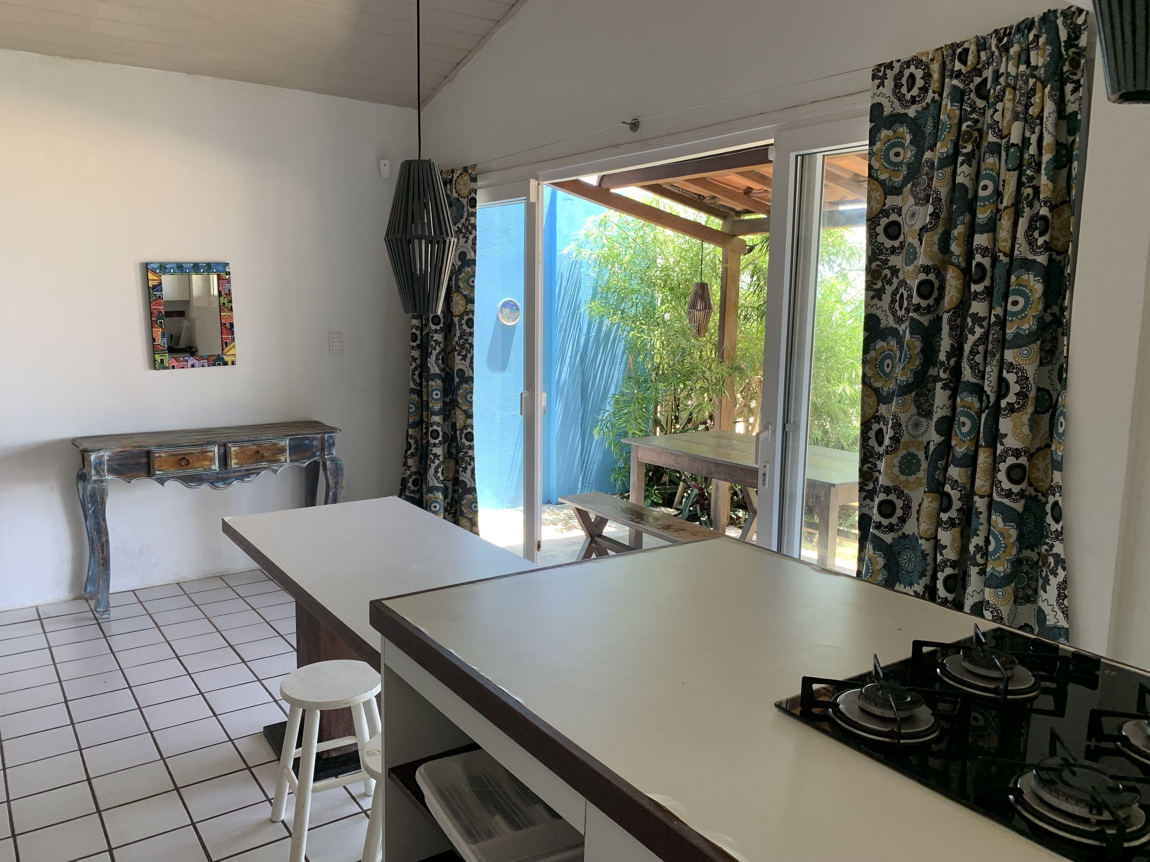 A kitchen with a white countertop, a stove, and a window with patterned curtains.