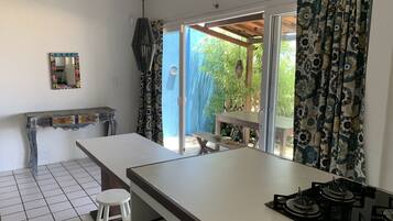 A kitchen with a white countertop, a stove, and a window with patterned curtains.