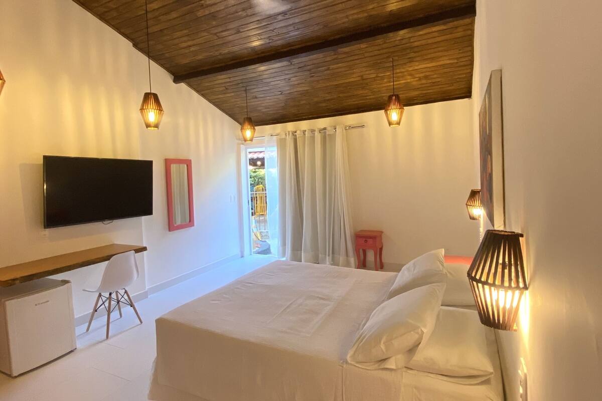 Un dormitorio con cama, escritorio, televisor y ventilador de techo.
