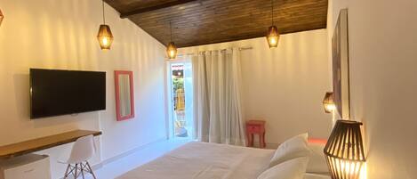 A bedroom with a bed, a desk, a television, and a ceiling fan.