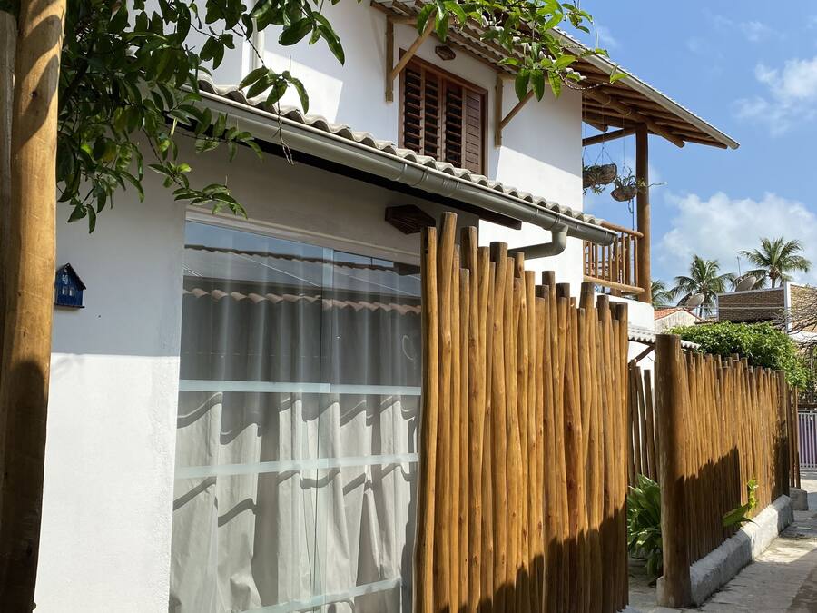 A house with a white exterior, a wooden balcony, and a stone-paved entrance.