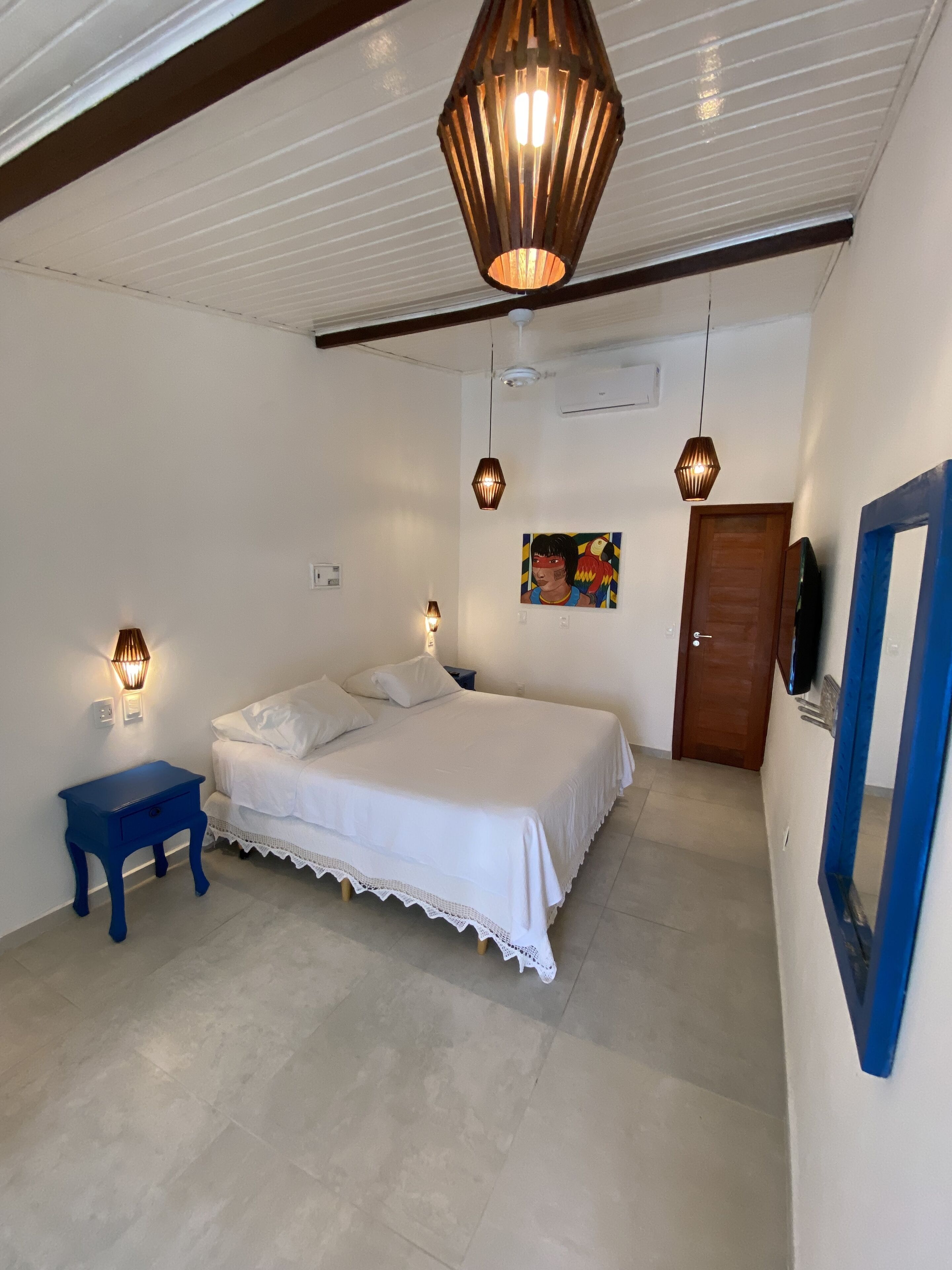 A bedroom with a bed, bedside tables, a painting, and a door.