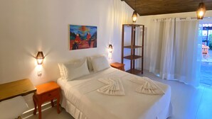 A bedroom with a wooden ceiling, a bed with white bedding, two bedside tables, a nightstand, a painting on the wall, and a view of the outside through a window with curtains. - Pousada Barbara (Tibau do Sul)
