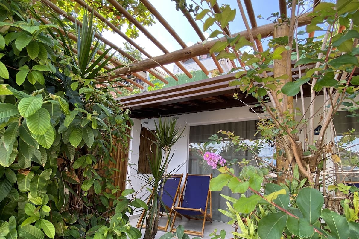 Un sendero en un jardín que conduce a un área de estar cubierta con una pérgola.
