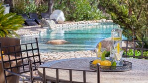 A poolside area with a round table, lounge chairs, and a drink tray with lemons and glasses. - Casa Del Sole Chambre d'hôtes de Charme (Sari-Solenzara)