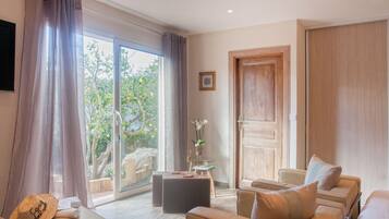A spacious living room with a large sliding glass door leading to a balcony, a comfortable sofa set, and a small side table with a vase.