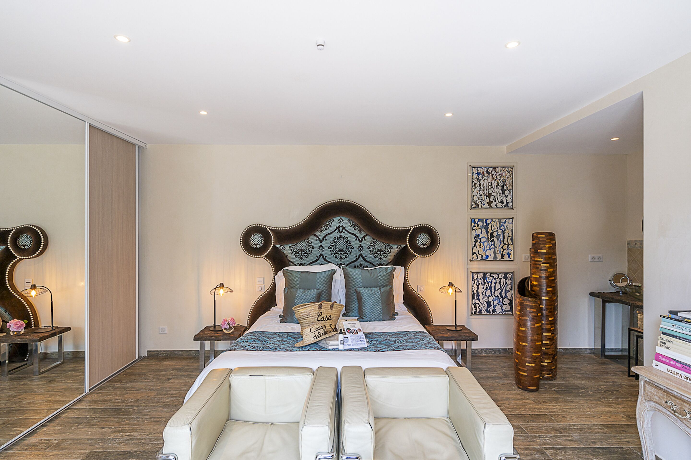 A bedroom with a large bed, bedside tables, a mirror, and decorative pillows.
