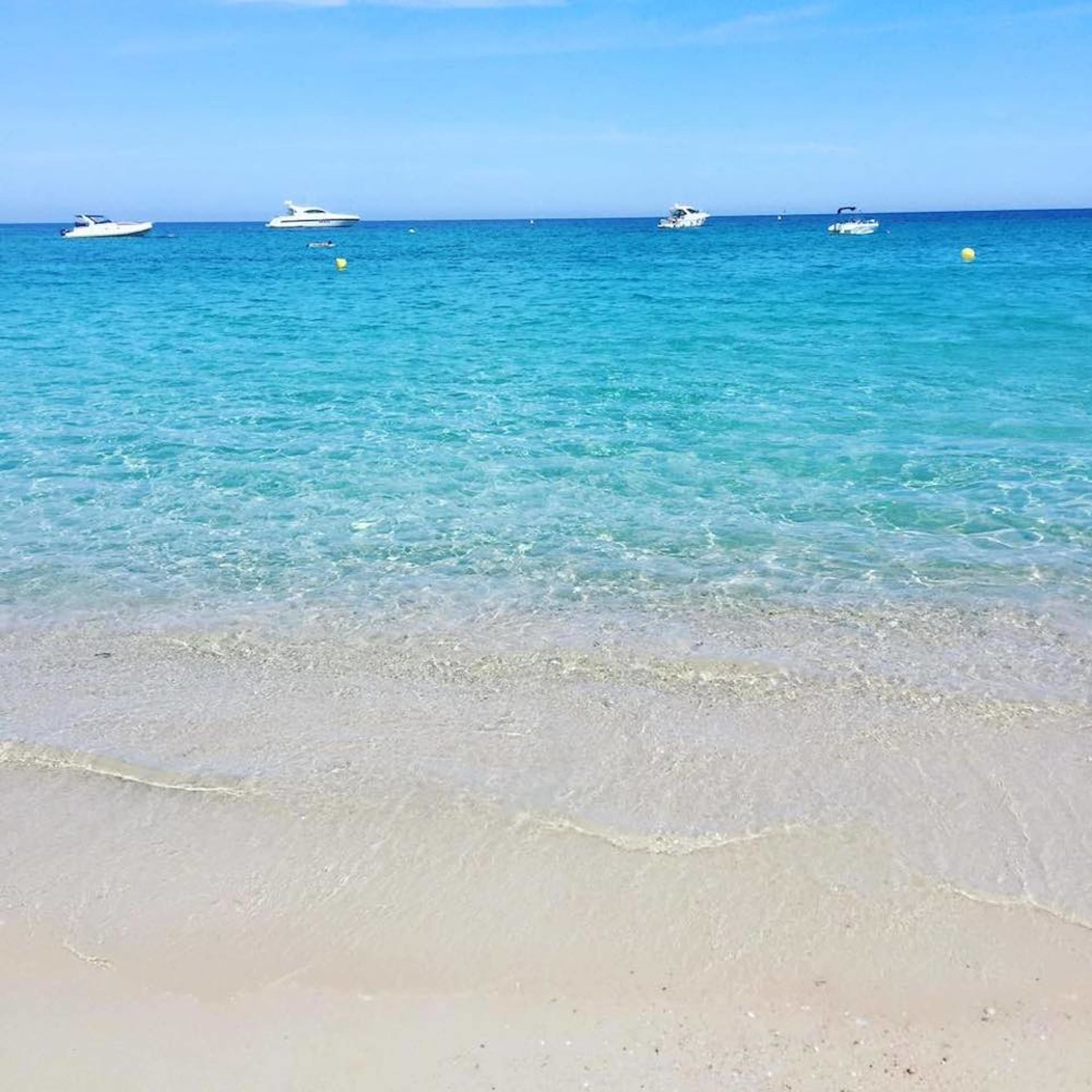 Una playa con aguas turquesas cristalinas y una orilla arenosa.