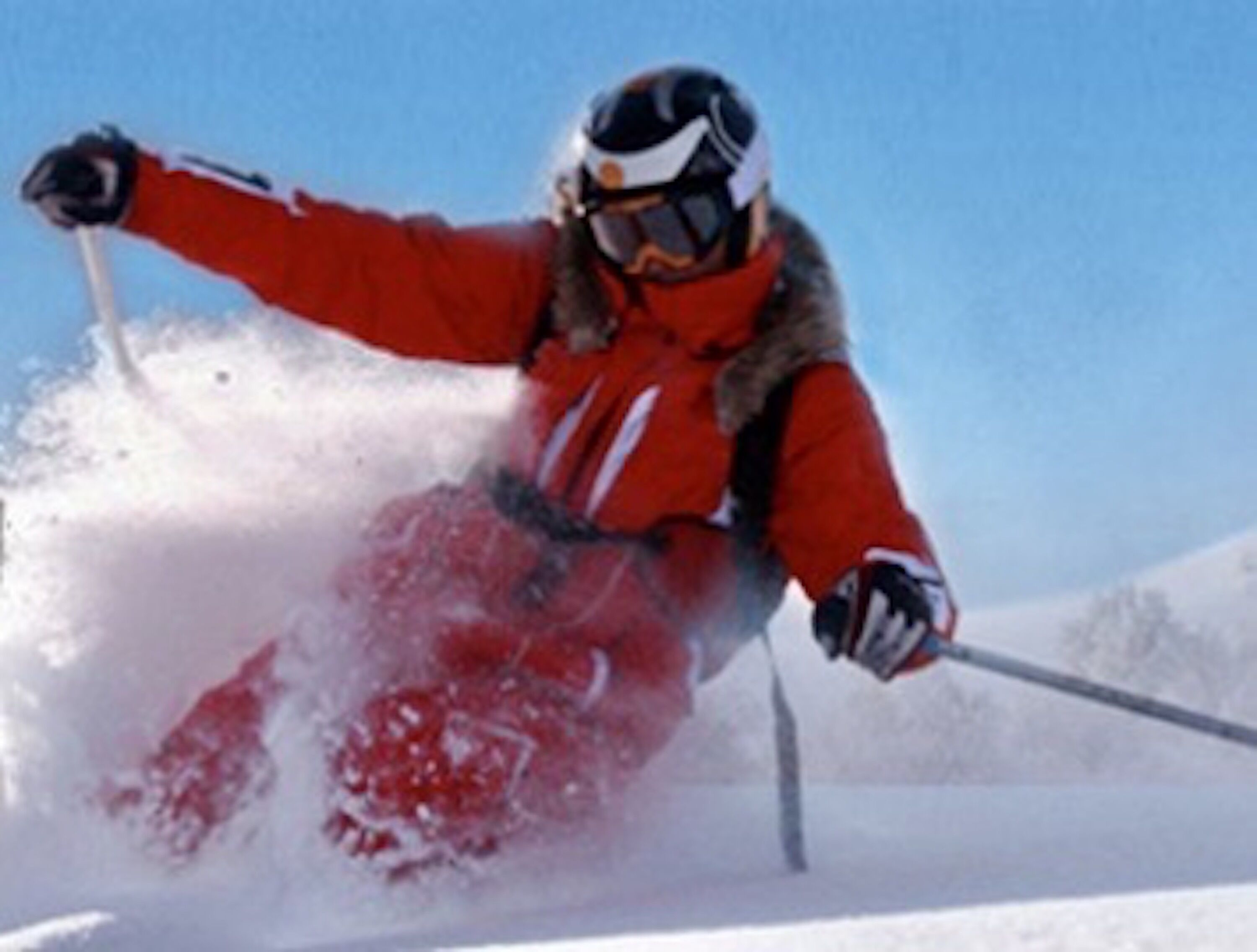 Eine Person fährt auf einem verschneiten Hang Ski.
