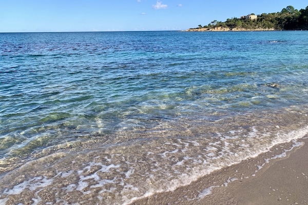 Perto da praia, areia branca, guarda-sóis, toalhas de praia