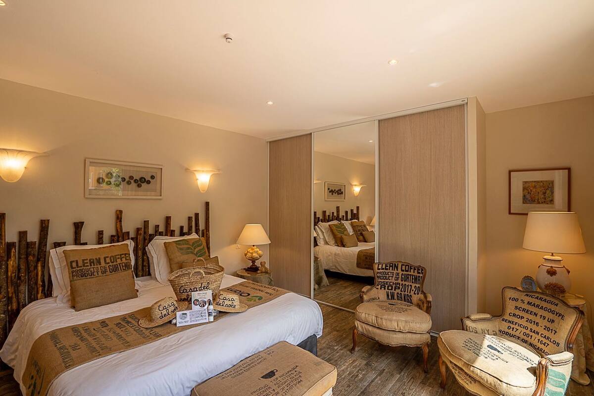 Ein Hotelzimmer mit einem Bett, zwei Stühlen, einem Spiegel und Wandlampen.