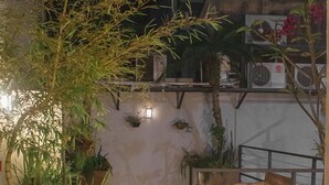 Un espacio exterior con plantas en macetas, un banco de madera y una escalera que lleva a un nivel superior.