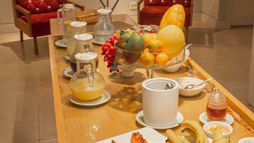A breakfast buffet with various fruits, pastries, and beverages.