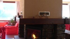 Una sala de estar con chimenea de piedra, un sofá rojo y una ventana con cortinas.