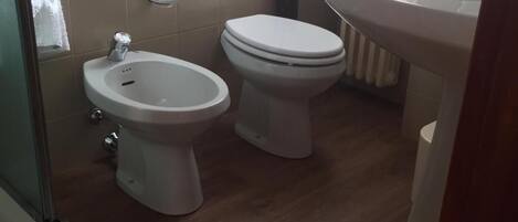 A bathroom with a bidet, toilet, and sink.
