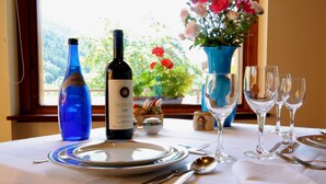 Una mesa dispuesta para comer, con botellas de vino, platos, cubiertos y copas.