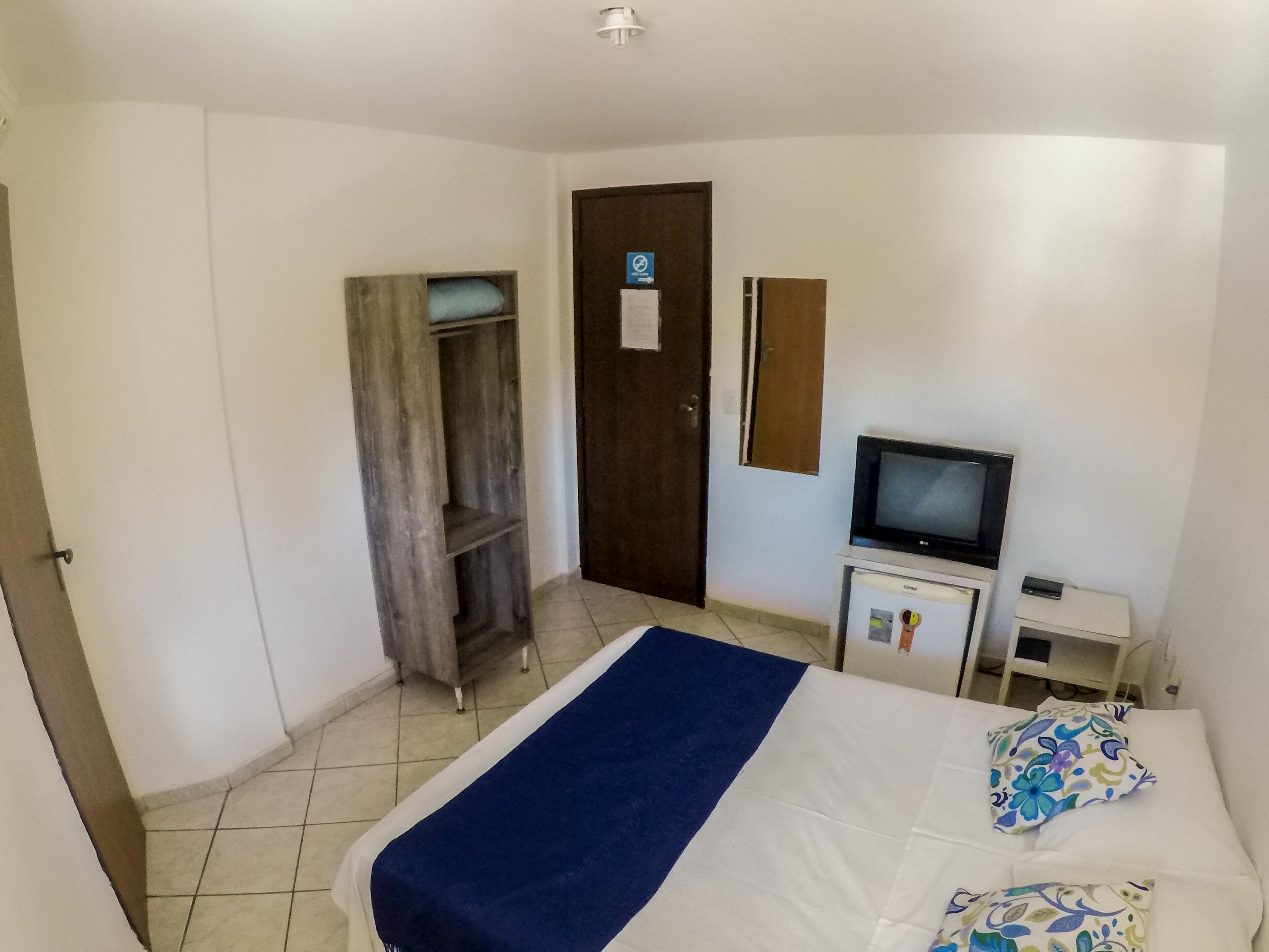 A bedroom with a bed, a TV, a desk, and a wardrobe.