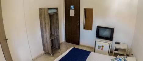 Un dormitorio con cama, televisor, escritorio y armario.