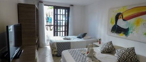 Una habitación de hotel con una cama, un televisor y un cuadro de un tucán.