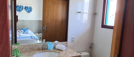 Une salle de bain avec un plan de toilette en marbre, un lavabo, des toilettes et une douche.