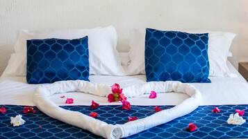 A neatly made bed with blue patterned pillows, a white comforter, and a decorative wall hanging above.