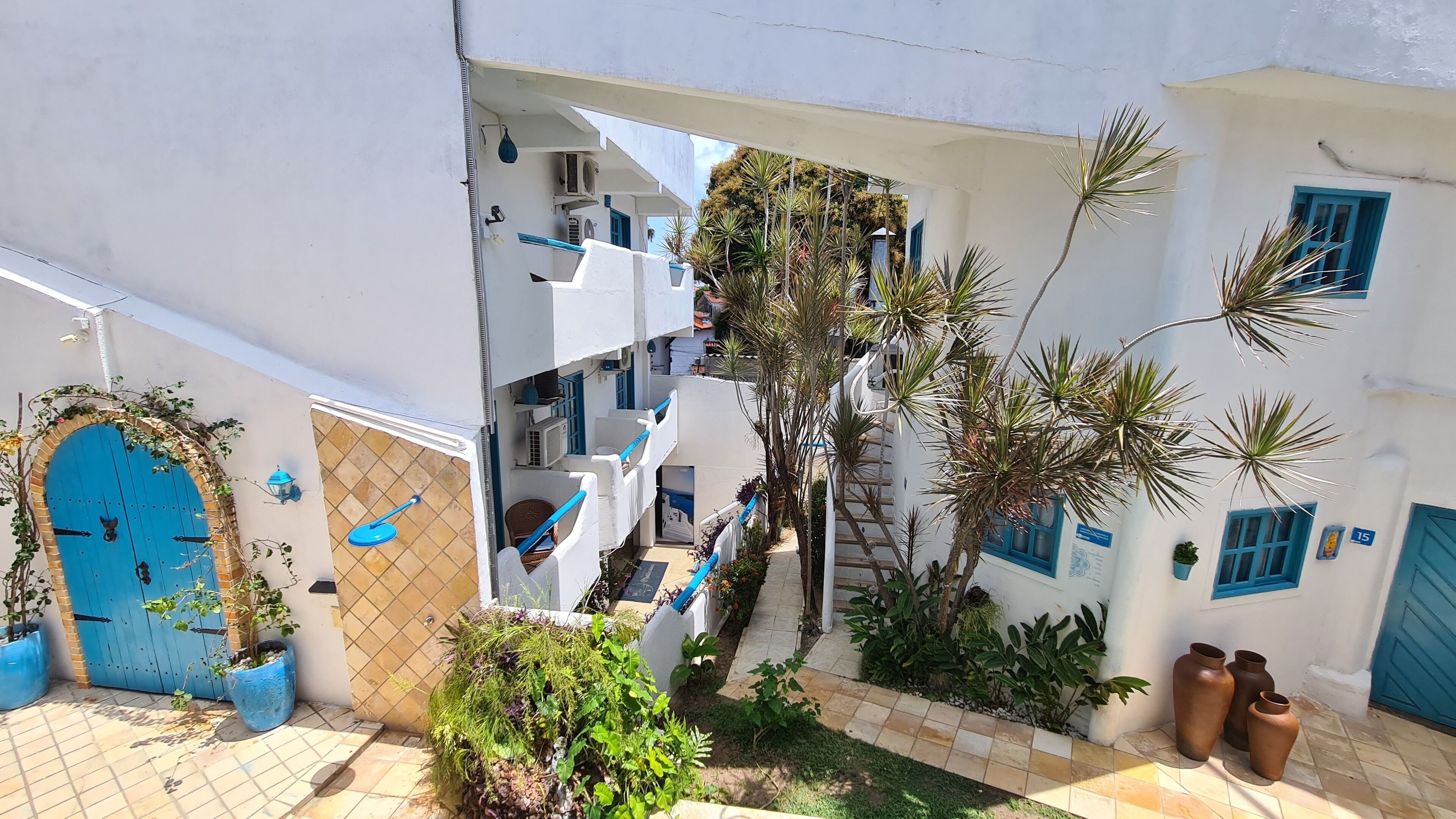 Un patio con edificios blancos, puertas azules y plantas en macetas.