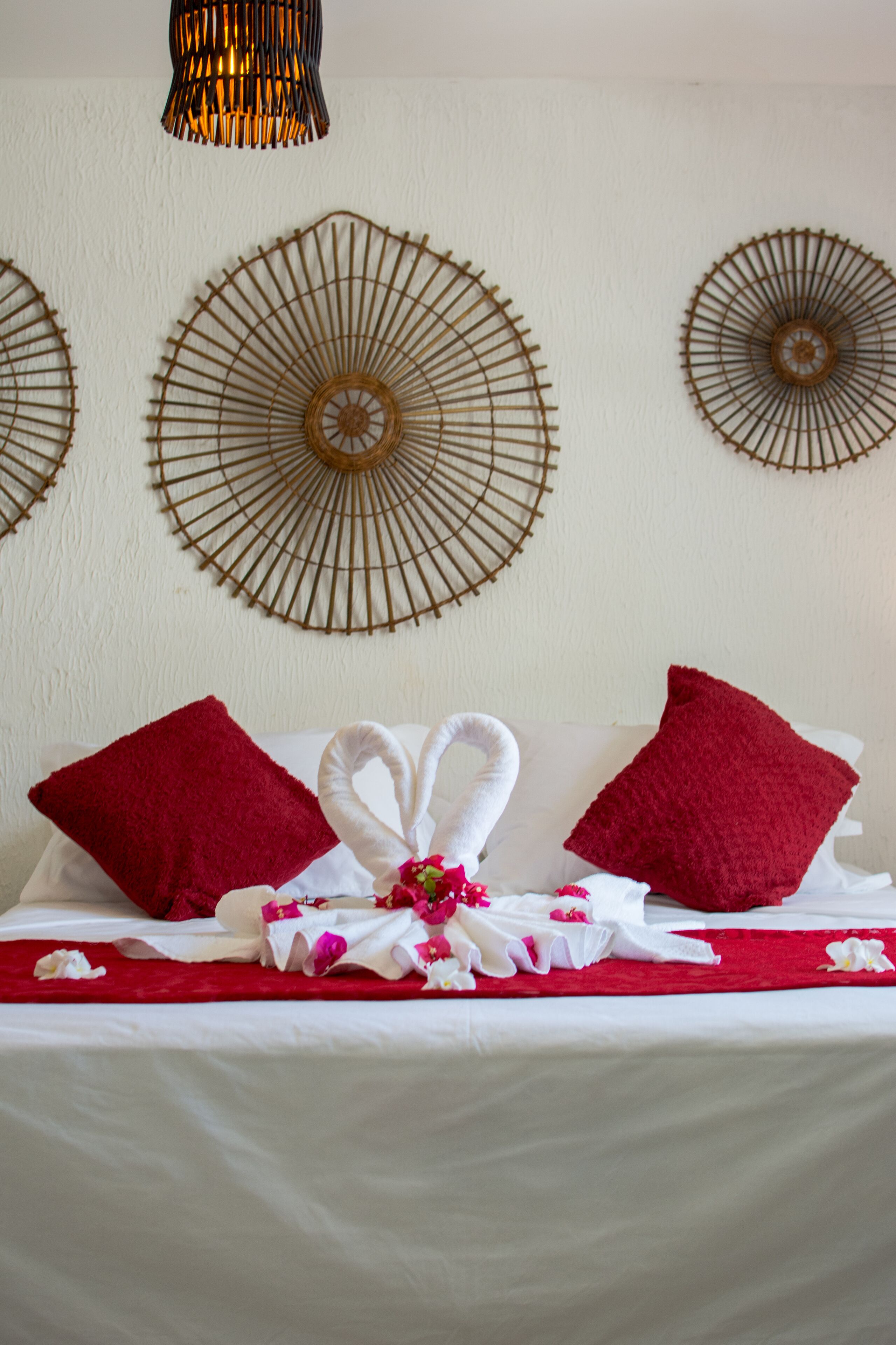 Una cama bien hecha con almohadas rojas, una toalla blanca y un adorno decorativo.