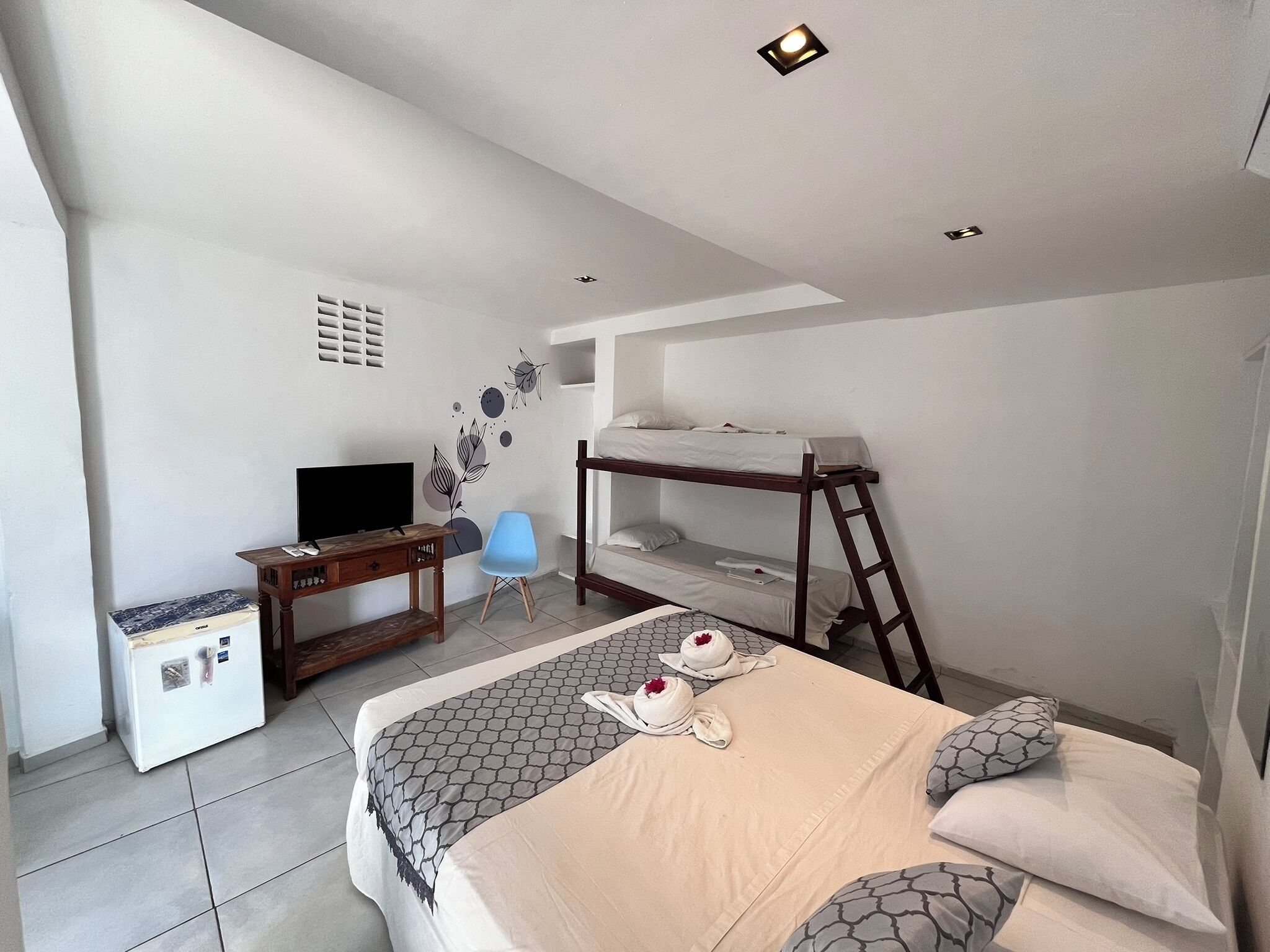 A bedroom with bunk beds, a desk, a chair, and a TV.