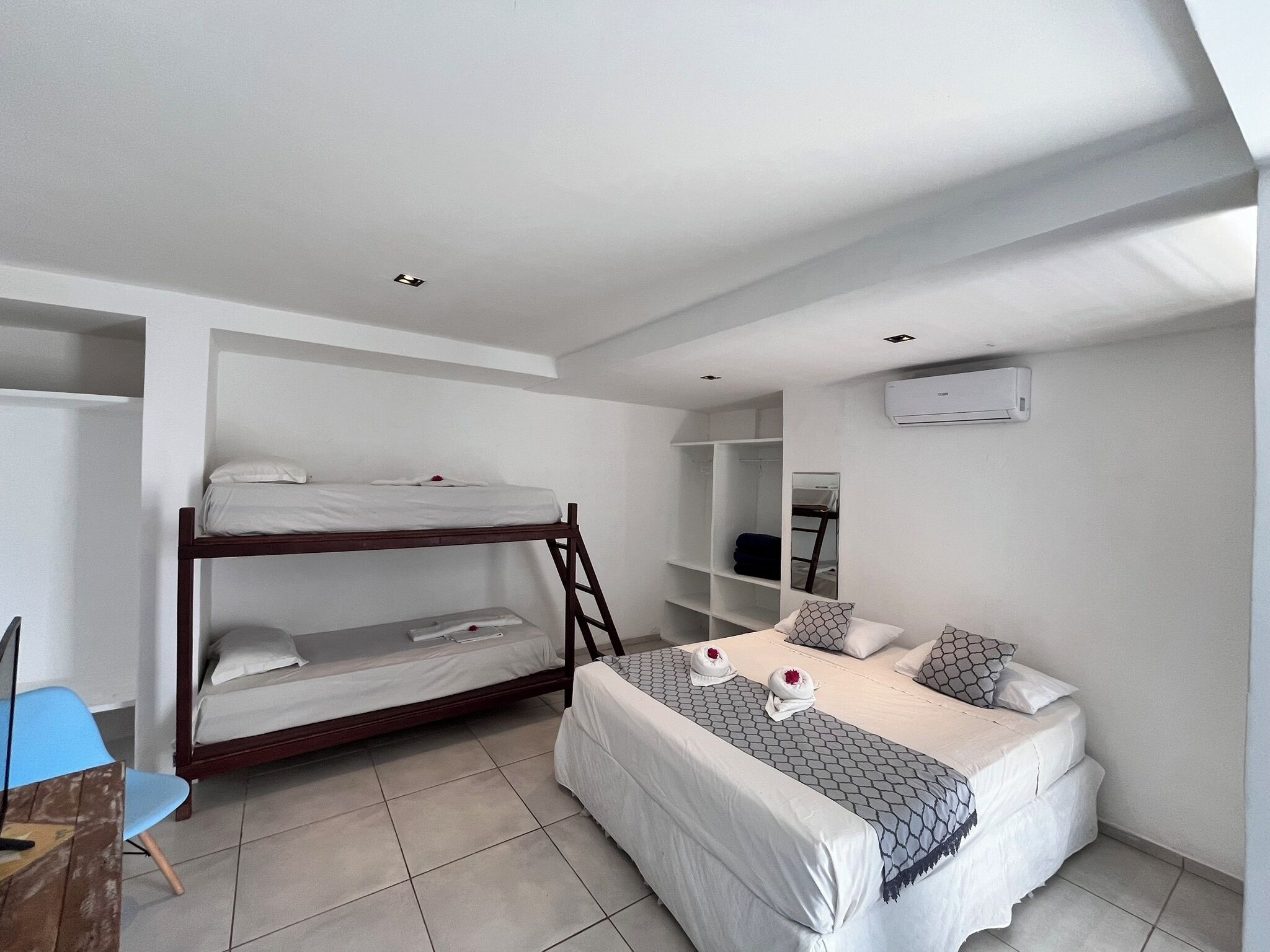 A bedroom with a bunk bed, a single bed, a desk, and a chair.
