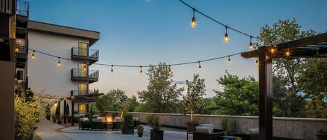 Eine Außenpatio-Terrasse mit Lichterketten, Sitzgelegenheiten und Blumentöpfen.
