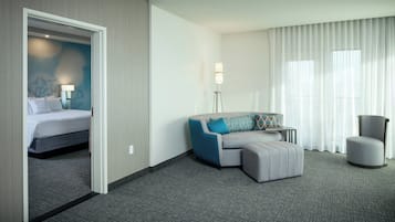 Een hotelkamer met een bed, een bank, een stoel en een vloerlamp.