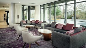 A modern lobby with a sectional sofa, armchairs, and a coffee table. Large windows offer a view of the outdoors. - Courtyard by Marriott Corvallis (Corvallis)