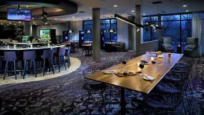 A modern hotel lobby with a bar, seating area, and large windows offering a view of the outdoors. - Courtyard by Marriott Corvallis (Corvallis)