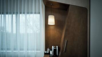 Ett modernt rum med ett träskåp, en kaffebryggare och en hängande lampa.