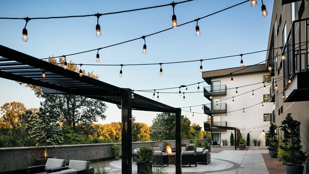 An outdoor patio area with string lights, seating, and potted plants. - Courtyard by Marriott Corvallis (Corvallis)