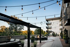 Eine Außenpatio-Terrasse mit Lichterketten, Sitzgelegenheiten und Blumentöpfen.