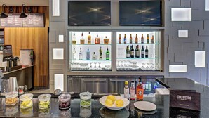 A bar area with a counter, shelves with bottles, glasses, and a menu board. - Courtyard by Marriott Appleton Riverfront (Appleton)