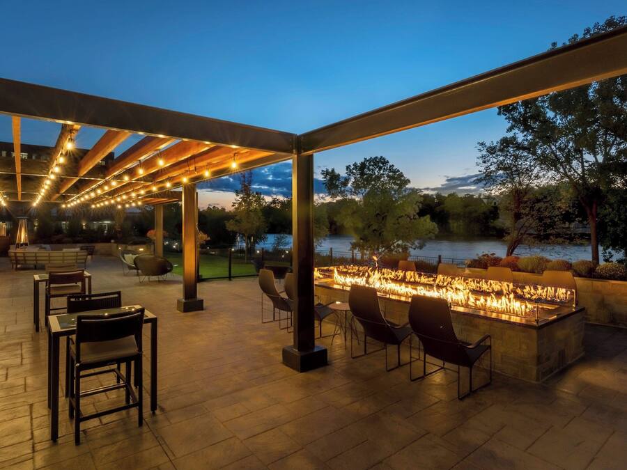 An outdoor patio with a fire feature, seating, and a view of a body of water.