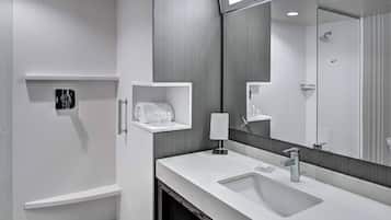 A modern bathroom with a large mirror, a white sink, and a shower.