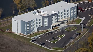 A Courtyard hotel with a parking lot, a road, and trees in the background.